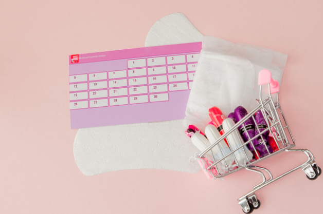 Calendar with tampons, pads, and liners against a pink background.